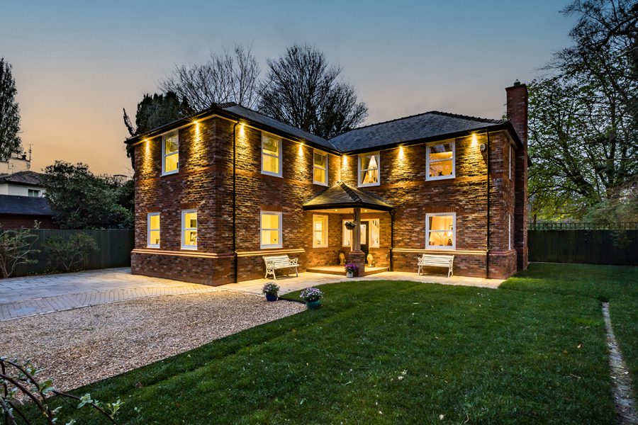 Front exterior of a prestigious detached home in Cheshire with illuminated driveway