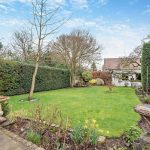 Rear exterior of period family home with patio and lawn in Cuddington.