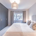 Bedroom featuring sleek fitted wardrobes, elegant grey tones and large window at 4 Bell Crescent, Davenham.