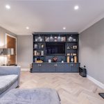 Bespoke fitted media wall with dark cabinetry and herringbone floor in a Davenham Cheshire home.