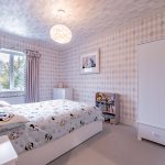 Children’s bedroom with diamond-pattern wallpaper, soft pastel tones and playful décor at 4 Bell Crescent, Davenham.