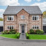 Front exterior of 4 Bell Crescent, Davenham, Cheshire — a detached family home framed by landscaped gardens and a central pathway.
