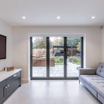 Family room with sofa and media unit looking onto landscaped garden through wide sliding doors at 4 Bell Crescent, Davenham.