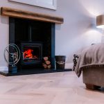 Elegant lounge fireplace with wood-burning stove and oak mantel in a modern Davenham Cheshire home.