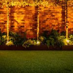 Evening garden scene with uplighting on brick wall and lush planted border at 4 Bell Crescent, Davenham.