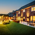 Outdoor kitchen and lounge area at 4 Bell Crescent, property for sale in Davenham, Cheshire, featuring an illuminated pergola, bar seating and manicured lawn.