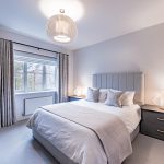 Guest bedroom with neutral palette, modern lighting and large window at 4 Bell Crescent, Davenham, Cheshire.