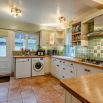 Shaker-style kitchen with wooden worktops and green tiled splashback in a Hartford detached family home.