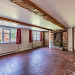 Characterful lounge at Gladstone Cottage featuring an exposed brick fireplace and period beams.