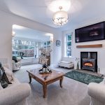 Lounge with log-burning stove, wall-mounted TV and opening to garden room at Kennelwood.