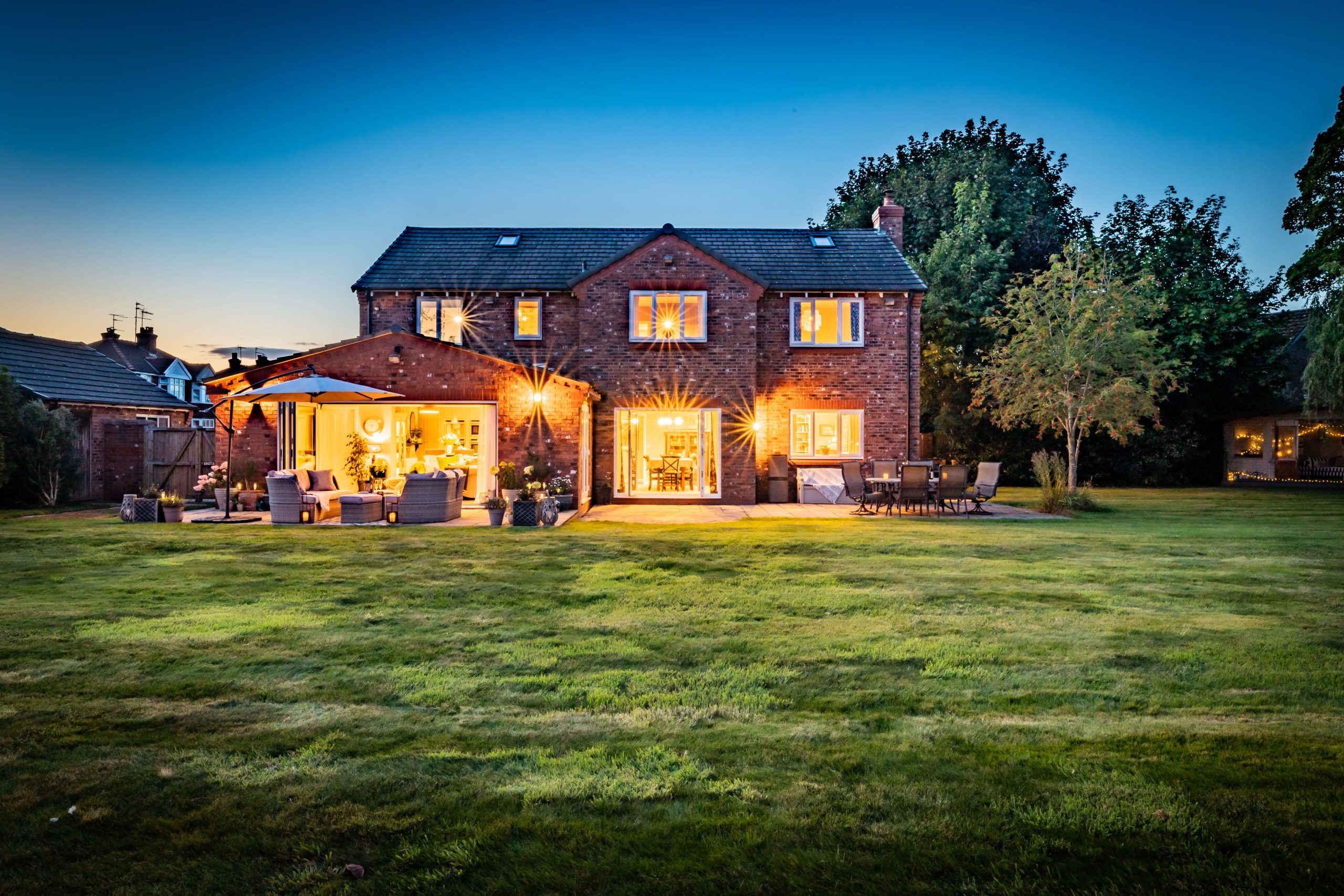 Full rear elevation at twilight, showing the home’s garden terrace and warm internal glow.