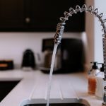 Close-up of a chrome kitchen tap with running water and minimalist countertop in a Davenham Cheshire home.