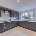 Grey modern kitchen with corner sink beneath window and integrated appliances at 4 Bell Crescent, Davenham, Cheshire.