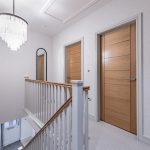 First-floor landing at 4 Bell Crescent, Davenham, Cheshire showcasing oak doors, glass chandelier and contemporary staircase detail.