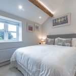 Serene guest bedroom with soft-grey palette, exposed beam and countryside outlook at a luxury barn conversion in Cuddington, Cheshire.