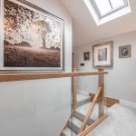 Light-filled landing with glass balustrade, oak detailing and skylight at a high-spec barn conversion in Cuddington, Cheshire.