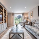 Stylish living room with patterned sofas and full-height glazing opening to the garden — part of a luxury barn conversion in Cuddington, Cheshire.