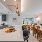 Luxury barn conversion in Cuddington, Cheshire — open-plan kitchen and dining area with quartz island, oak dining table and contemporary pendant lighting, presented by J Lord & Co.