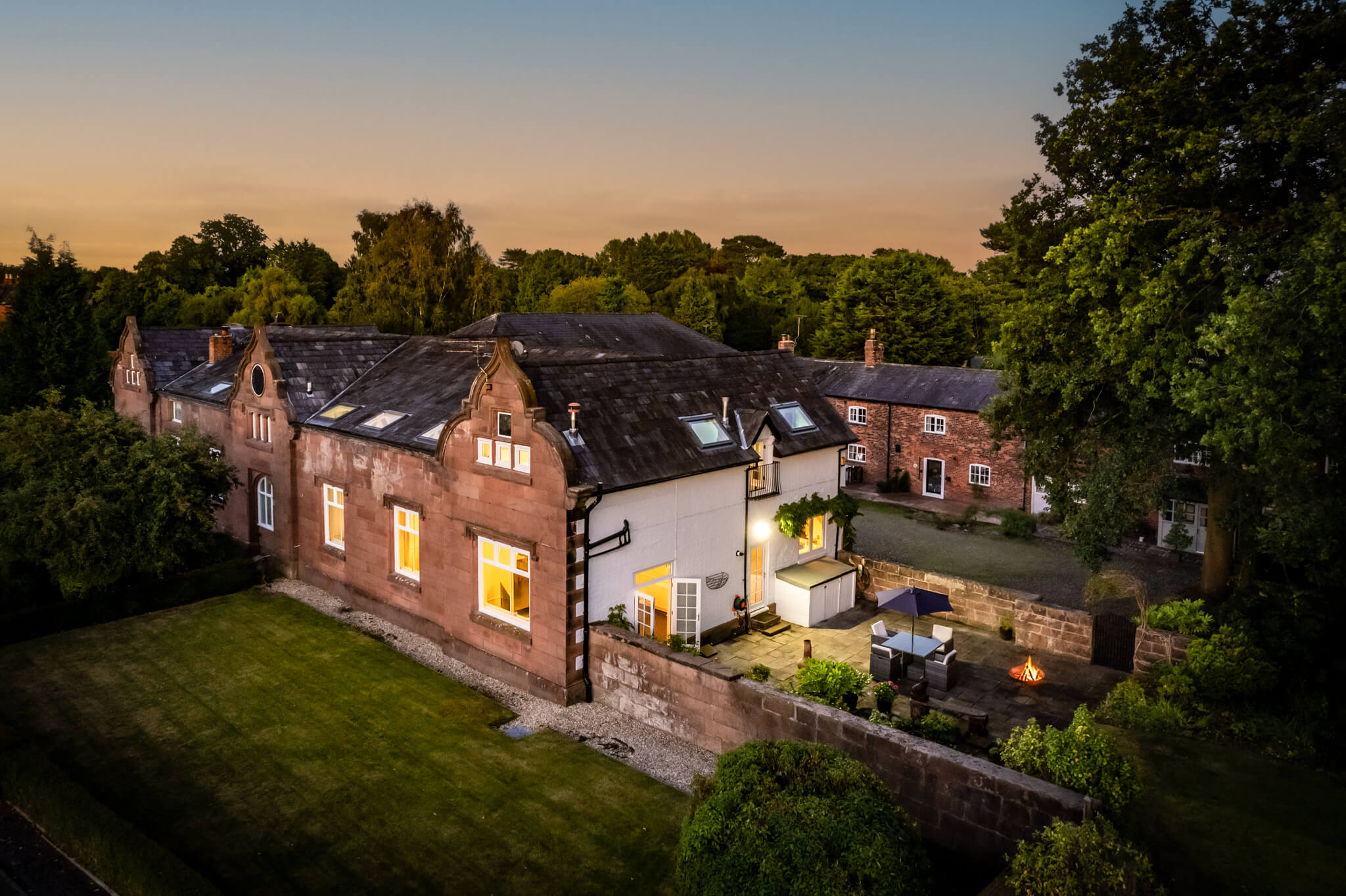 Elevated drone view of a luxury barn conversion in Whitegate with sandstone façade, slate roof and private terrace.