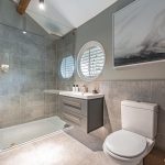 Contemporary bathroom at Blossoms, Bostock featuring circular window, walk-in shower, and neutral tones.