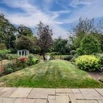 Expansive garden with manicured lawn, mature shrubs and wooden fencing at Blossoms, Bostock — luxury Cheshire home.