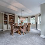 Luxury home in Northwich featuring a stylish dining room with bay windows, oak flooring, and warm neutral tones.