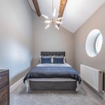 Guest bedroom with porthole window and vaulted ceiling at Blossoms, Bostock — Luxury Cheshire Home.