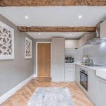 Modern kitchen with marble splashback, shaker cabinetry and exposed beams at Blossoms, Bostock.