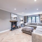 Spacious open-plan lounge with herringbone flooring, modern fireplace and sectional sofa in a Davenham Cheshire property for sale.