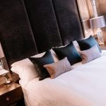 Luxury principal bedroom featuring tall velvet headboard, bedside lamps and layered textures in a Davenham Cheshire home.
