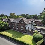 Front elevation of sandstone barn conversion in Whitegate with manicured lawn, hedging and character façade.
