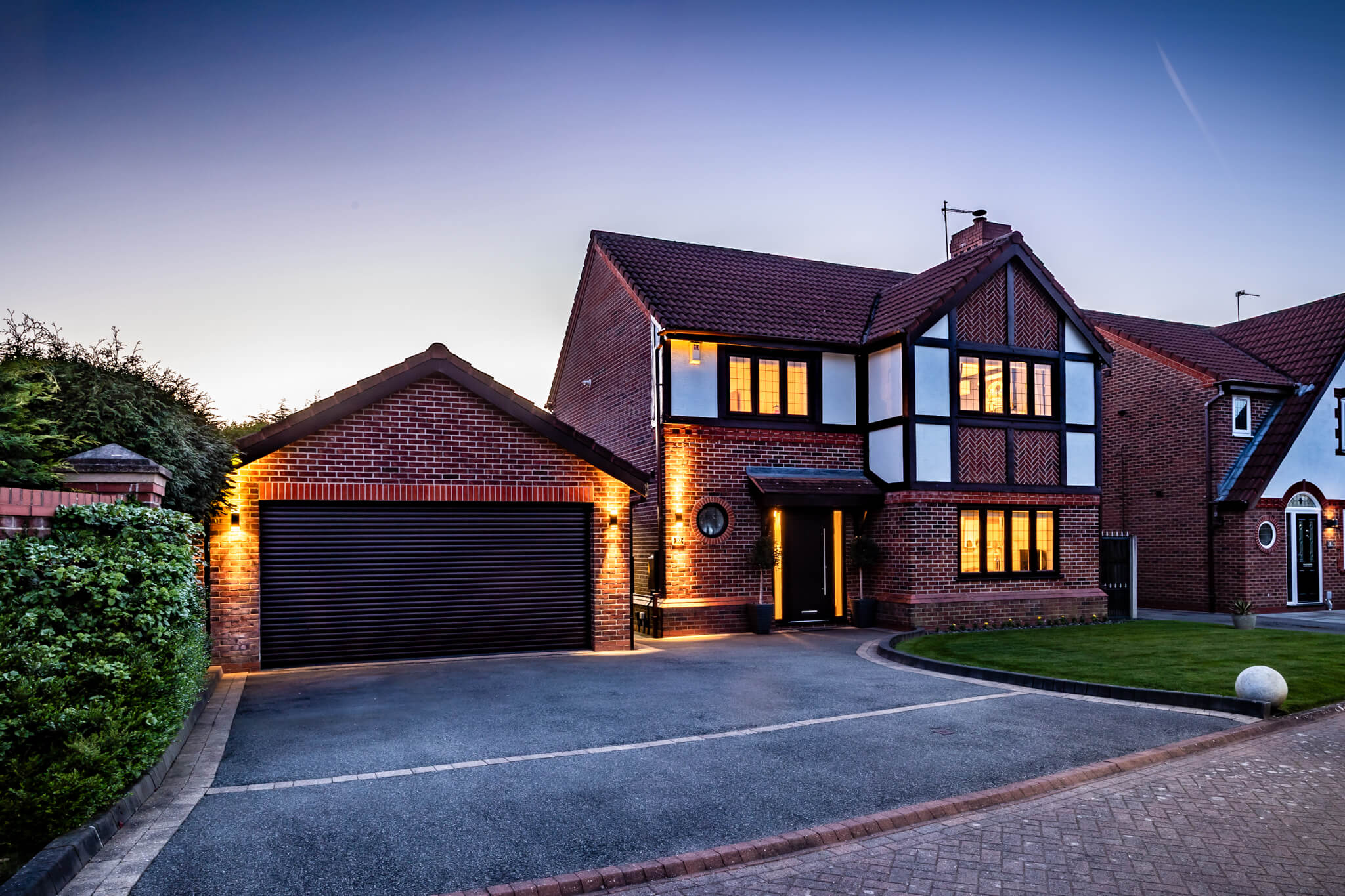 Twilight exterior of a detached property for sale Kingsmead Cheshire showing warm interior lighting