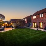 Rear garden at twilight showing outdoor seating and lawn at a property for sale Kingsmead Cheshire.