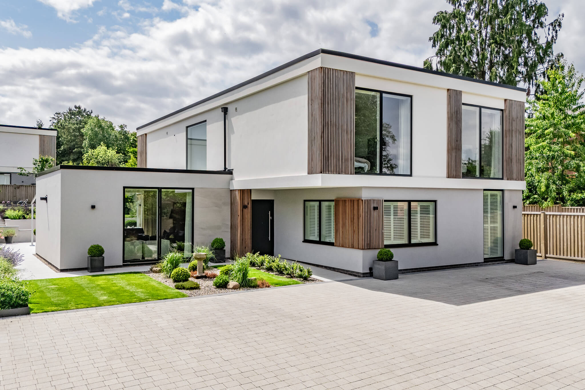 Front exterior of the contemporary Sandiway Park home with clean architectural lines, timber detailing and landscaped approach