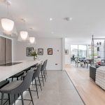 Dining room with full garden views through sliding glazing, featuring contemporary seating and a glass dining table.