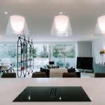 Wide view of open-plan kitchen, dining and living space with pendant lighting and seamless garden connection.