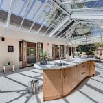 Glass roof orangery creating light-filled kitchen and dining space in Hartford luxury home.