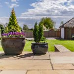 Stone patio with planted pots overlooking lawn and garden space in Davenham property