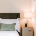 Bedroom bedside table with soft lighting, neutral tones and layered textures creating a calm and restful setting