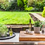 Outdoor preparation area with herbs and condiments, overlooking the garden for alfresco cooking