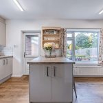 Modernised kitchen within this four-bedroom detached home in Davenham, featuring contemporary cabinetry, breakfast bar seating and views across the rear garden.