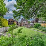 Rear garden view looking back toward this detached family home in Davenham, showcasing the established plot, mature planting and private outdoor setting.