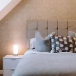 Bedroom detail at The Barns, Bostock Hall Estate, with upholstered headboard, soft lighting and contemporary finishes