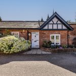 Character cottage frontage at The Barns, Bostock Hall Estate, featuring traditional architecture, landscaped borders and courtyard approach