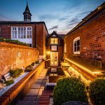 Landscaped rear garden at The Barns, Bostock Hall Estate, featuring lawned garden, patio terraces and evening lighting