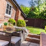 Rear patio seating area at The Barns, Bostock Hall Estate, featuring outdoor dining space, landscaped planting and private garden setting