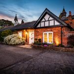 Twilight front elevation of a character home within The Barns at Bostock Hall Estate, featuring traditional brick architecture and landscaped frontage