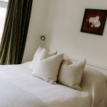 Principal bedroom with layered cushions and soft natural styling