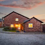 Front elevation of Pear Tree Farm in Davenham at sunset with warm interior lighting.