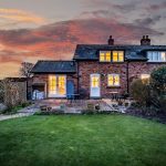 Rear elevation of Pear Tree Farm in Davenham at dusk with illuminated windows and landscaped garden